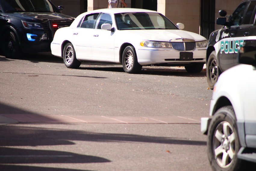 A white Lincoln sedan sits amid police cars near the Kent Place apartments at East Hampden Avenue and South University Boulevard on Oct. 14. A suspect stole the car in Lakewood two days earlier and ran over two elderly women, who remained hospitalized as of late afternoon Oct. 14.